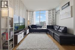 Bright living area featuring large windows with city exposure, light wood-finish flooring, and a patterned accent wall - 