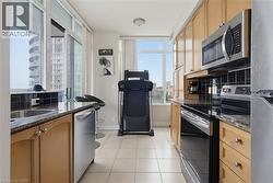 Kitchen featuring light wood cabinetry, granite-style countertops, stainless steel appliances, and a black tile backsplash - 