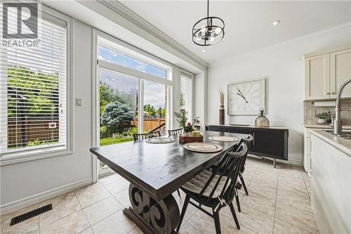 Dining area featuring large sliding glass doors opening to the exterior, tile flooring, crown molding, a modern overhead light fixture, and recessed lighting - 20 Degrow Crescent, Binbrook, ON 