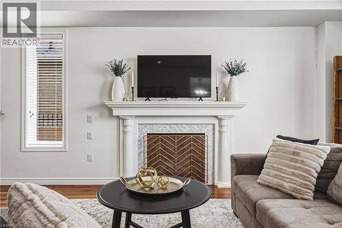 Fireplace with classic white mantel, marble surround, and decorative metal screen - 20 Degrow Crescent, Binbrook, ON 