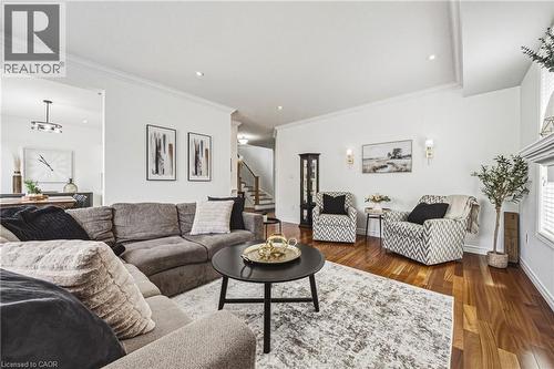 Open-concept living area featuring rich wood-finish flooring, crisp white walls, recessed lighting, and crown molding - 20 Degrow Crescent, Binbrook, ON 