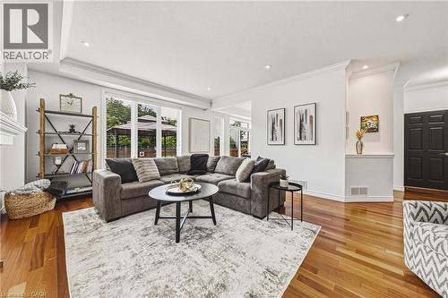 Open-concept living area featuring rich wood-finish flooring, a contemporary ceiling with recessed lighting, and crown molding - 20 Degrow Crescent, Binbrook, ON 