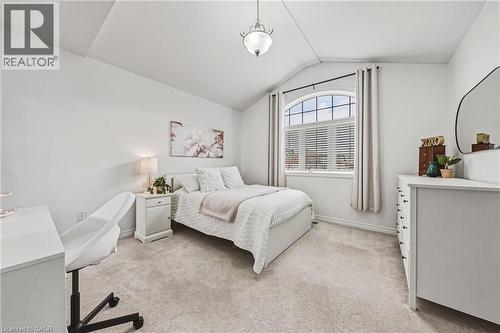 Carpeted bedroom featuring an arched window with blinds and drapes - 20 Degrow Crescent, Binbrook, ON 