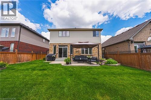Spacious backyard featuring a manicured lawn, stone patio, and privacy fencing - 20 Degrow Crescent, Binbrook, ON 