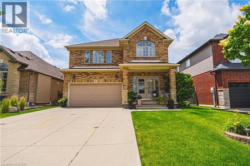 Brick and stone facade residence featuring an arched window, covered entryway, and an attached two-car garage - 20 Degrow Crescent, Binbrook, ON 