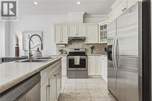 Kitchen featuring light-toned cabinetry, stainless steel appliances, a double basin sink with a high-arc faucet, a tiled backsplash, and recessed lighting - 20 Degrow Crescent, Binbrook, ON 