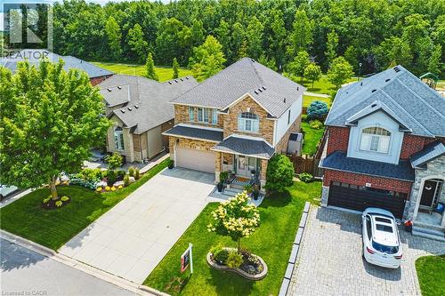 Two-story residential property featuring a brick and stone facade, an attached garage, a paved driveway, and a manicured lawn - 20 Degrow Crescent, Binbrook, ON 