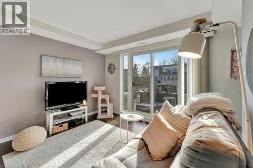 Living area with wood-finish flooring and a sliding glass door opening to an exterior balcony - 236 Rachel Crescent Unit# E, Kitchener, ON 