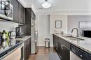 Kitchen featuring dark wood-finish cabinetry, light speckled countertops, and stainless steel appliances - 236 Rachel Crescent Unit# E, Kitchener, ON 