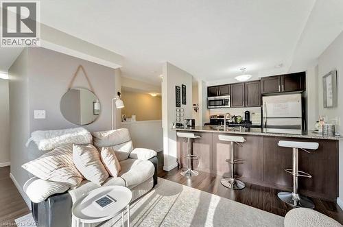Open-concept living space featuring wood-finish flooring, a kitchen island with seating, dark wood cabinetry, and stainless steel appliances including a refrigerator and microwave - 236 Rachel Crescent Unit# E, Kitchener, ON 
