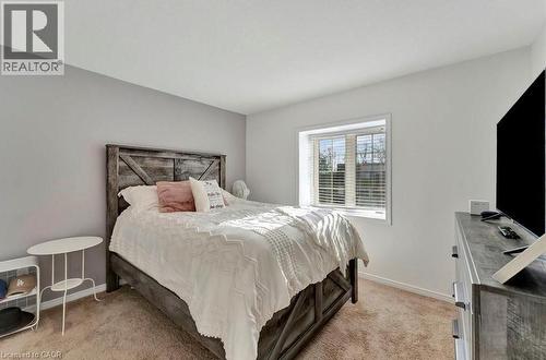 Carpeted bedroom with a window featuring blinds, complemented by a wood-finish bed frame and a contrasting accent wall - 236 Rachel Crescent Unit# E, Kitchener, ON 