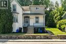 Two-story residence featuring a bay window, stucco siding, and a covered porch with railings - 66 Queen Street W, Cambridge, ON 