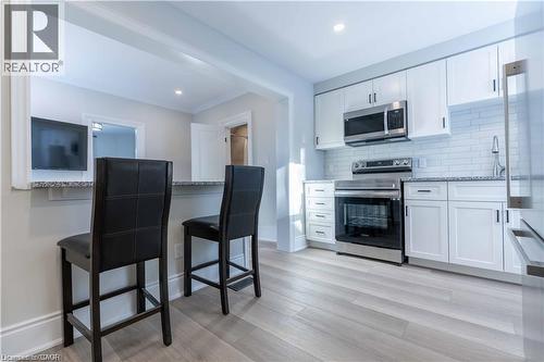 Kitchen featuring white shaker cabinetry, stainless steel appliances, and subway tile backsplash - 66 Queen Street W, Cambridge, ON 