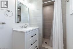 Bathroom featuring a white vanity with a speckled countertop, undermount sink, and brushed nickel faucet - 