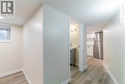 Wood-finish flooring throughout, with a window providing natural light, a compact kitchen area featuring stainless steel appliances, and a bathroom with a vanity and wall-mounted light fixture - 