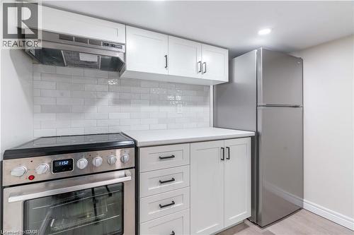 Stainless steel appliances, including a range and refrigerator, complement the white shaker-style cabinetry - 66 Queen Street W, Cambridge, ON 