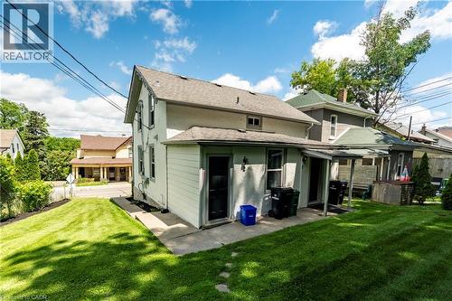 Rear exterior of a two-story residence featuring a concrete patio, a covered porch, and a manicured lawn - 66 Queen Street W, Cambridge, ON 