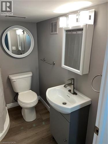Compact bathroom featuring a white toilet, contemporary wall vanity, and white basin with a single-handle faucet - 66 Queen Street W, Cambridge, ON 