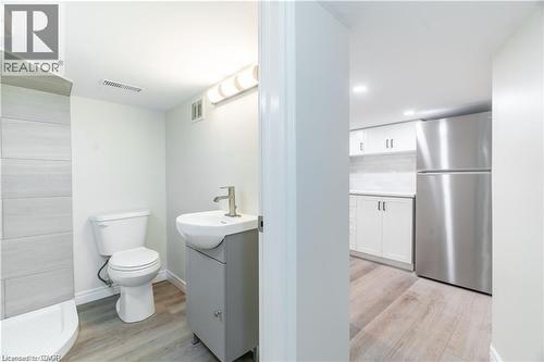 Bathroom featuring a white toilet, contemporary vanity with a white vessel sink, and an adjacent shower with horizontal tile detailing - 66 Queen Street W, Cambridge, ON 