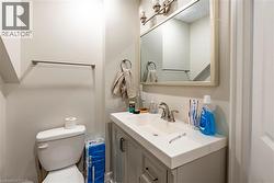 Bathroom featuring a white integrated sink, a light gray vanity with brushed nickel hardware, and a framed mirror with a three-light vanity fixture - 
