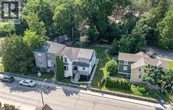 Two-story property featuring light gray siding with white trim, a gabled roof, and a front porch - 