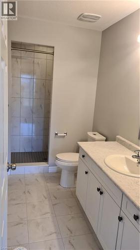 Modern bathroom featuring a walk-in shower with tile surround, a single vanity with an integrated sink, white cabinetry, and light-toned tile flooring - 42 Wheat Lane Unit# 42, Kitchener, ON 