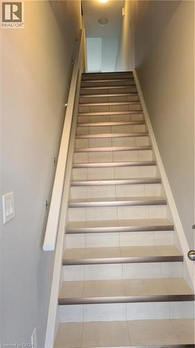 Staircase featuring light-toned tile treads with metal nosing and a painted handrail - 42 Wheat Lane Unit# 42, Kitchener, ON 