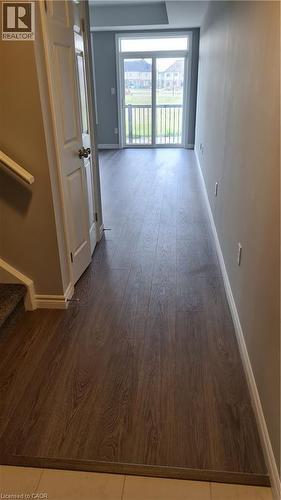 Wood-finish flooring extending to a sliding glass door with a balcony, presenting a view of exterior residences - 42 Wheat Lane Unit# 42, Kitchener, ON 