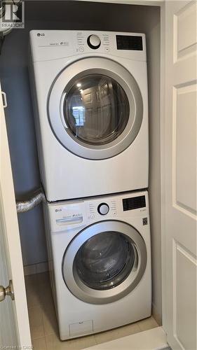 Dedicated laundry closet featuring a stacked white front-load washer and dryer set, compact design, and light-toned tile flooring - 42 Wheat Lane Unit# 42, Kitchener, ON 