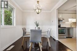 Formal dining area featuring rich wood-finish flooring, wainscoting, and crown molding - 