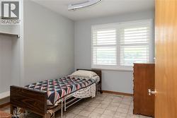 Room with light gray walls, an open closet with shelving and hanging rod, and a window featuring white plantation shutters - 