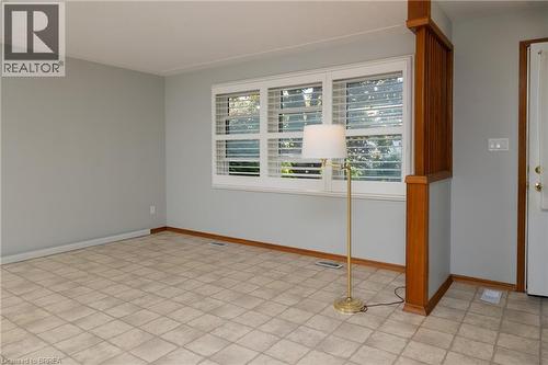 Kitchen featuring white cabinetry, a double basin stainless steel sink, a gas range with an overhead exhaust, and a window with exterior tree scenery - 156 Mutual Street N, Ingersoll, ON 