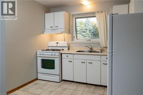 Room with light gray walls, an open closet with shelving and hanging rod, and a window featuring white plantation shutters - 156 Mutual Street N, Ingersoll, ON 