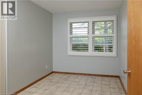 Room featuring light gray walls, two windows with white curtains, patterned flooring, and wood baseboards - 156 Mutual Street N, Ingersoll, ON 
