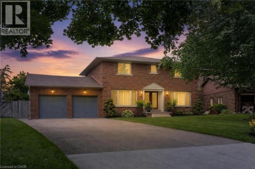 Brick-clad two-story residence featuring a two-car garage, concrete driveway, and front lawn - 7 Thomson Road, Simcoe, ON 