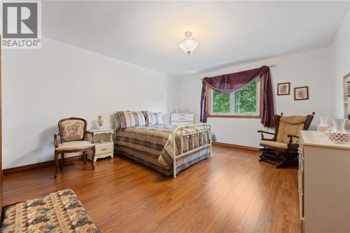 Spacious room featuring wood-finish flooring, white walls, and a large window with wood trim - 7 Thomson Road, Simcoe, ON 
