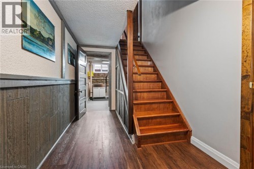 Wood-finish flooring throughout, featuring a hardwood staircase with a matching railing - 7 Thomson Road, Simcoe, ON 