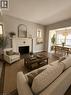 Living room featuring wood-finish flooring, a white fireplace with patterned tile surround, and neutral wall paint - 947 Main Street E, Hamilton, ON  - Indoor Photo Showing Living Room 