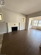 Living area featuring wood-finish flooring, a tiled fireplace surround, and multiple windows - 