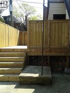 Elevated wood deck with privacy fencing, featuring a multi-step staircase and concrete patio access - 