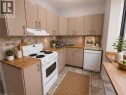 Kitchen featuring wood-finish countertops, neutral cabinetry, a tile backsplash, and a ceramic tile floor - 947 Main Street E, Hamilton, ON 