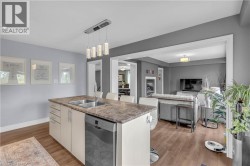 Kitchen island featuring a double-basin sink, integrated dishwasher, and seating for three - 