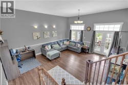 Spacious living area featuring high ceilings, wood-finish flooring, and bright natural light from multiple glass-paneled doors - 