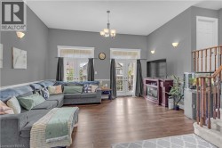 Spacious interior featuring a vaulted ceiling, wood-finish flooring, and multiple wall sconces providing ambient lighting - 