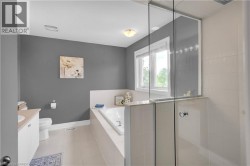 Soaking tub with tiled surround, framed window, and a glass-enclosed shower with tile walls - 
