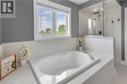 Bathroom featuring a built-in soaking tub with polished chrome fixtures, white tile surround, and a clear glass walk-in shower with a rain shower head - 