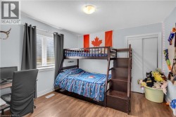 Bedroom featuring wood-finish flooring, a window with blinds, and a built-in closet with sliding doors - 