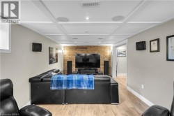Entertainment area featuring wood-finish flooring, a textured accent wall, coffered ceiling, recessed lighting, and built-in ceiling speakers - 