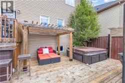 Expansive wooden deck featuring a built-in hot tub and a pergola - 