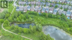 Aerial perspective showcasing a residential development bordering a natural pond and expansive green space - 